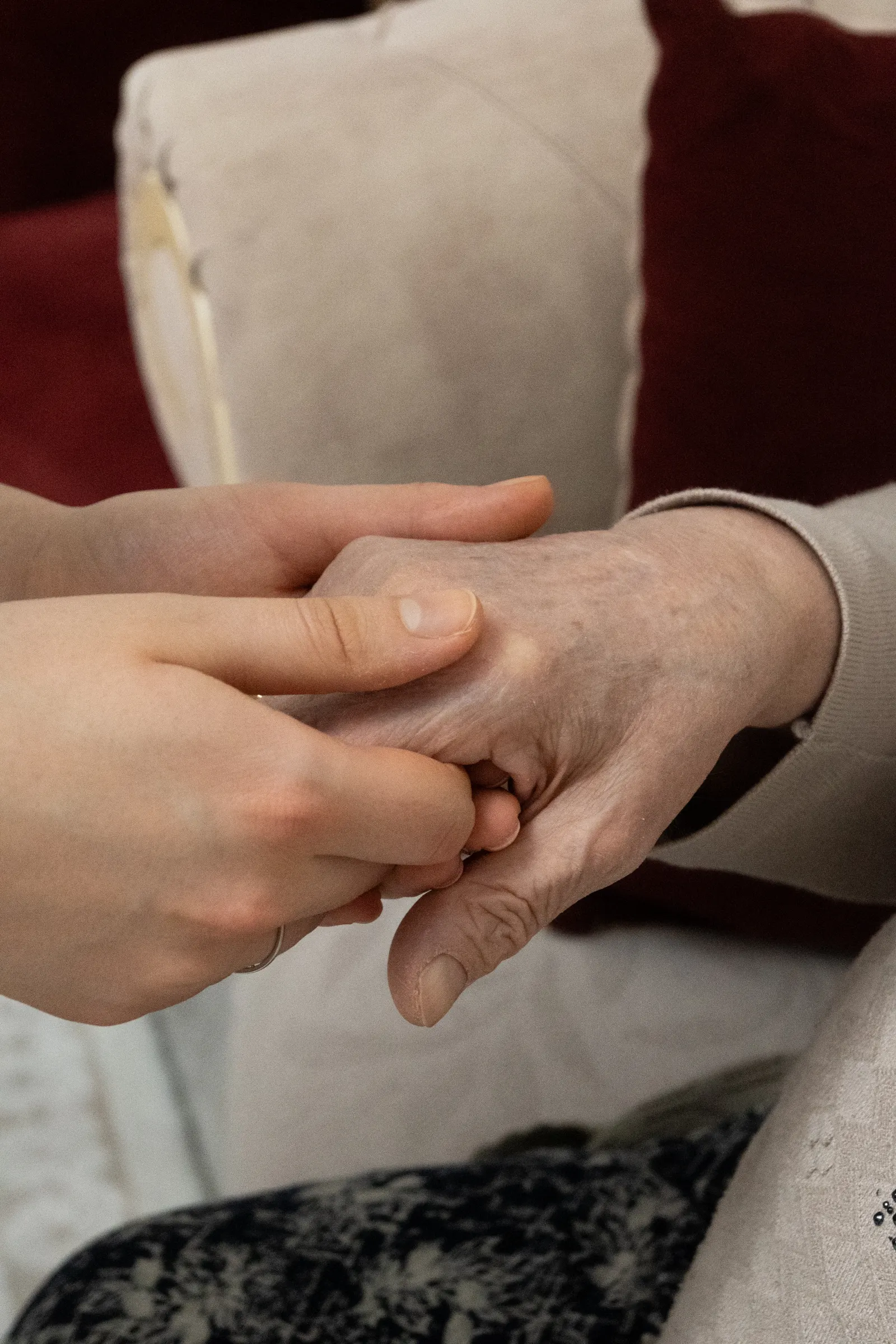 Close-up of a younger person gently holding an older person's hand