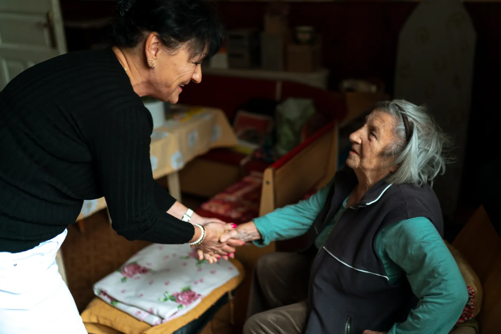 A carer warmly greets an older woman in her living room