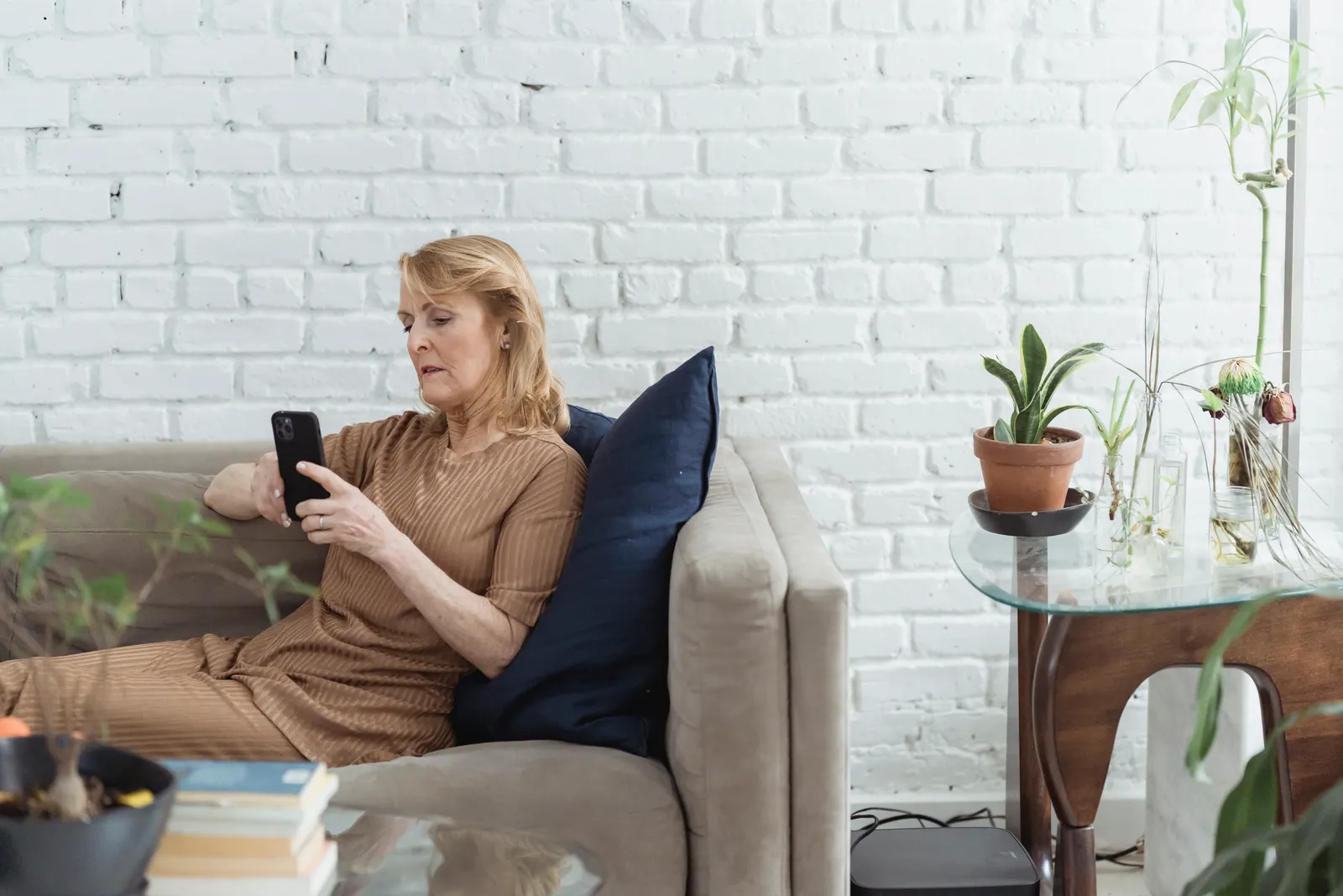 An older woman relaxing on her sofa at home, using her phone